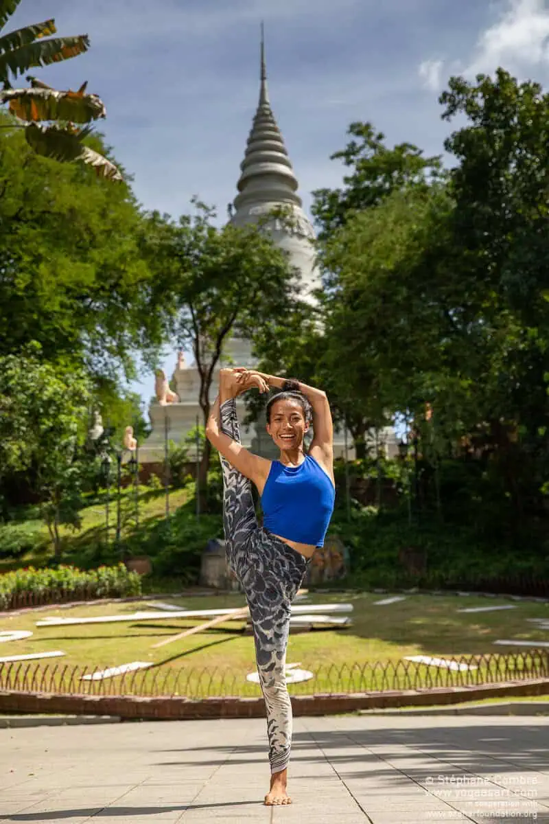 Yoga teacher Chhayleang Kauy in standing bow pose in front of a stupa in Phnom Penh, Cambodia