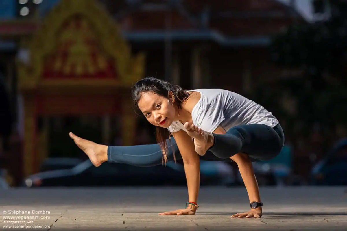 Yoga teacher Raty Khun in an arm balance pose outside a Cambodian temple